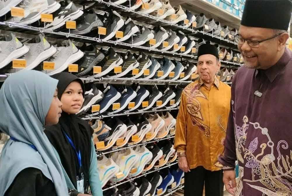 Haim Hilman (kanan) dan Saduruddin menyantuni anak yatim dan asnaf yang diberi peluang memilih baju dan kelengkapan hari raya di Mydin Taman Batik Sungai Petani Kedah pada Jumaat.