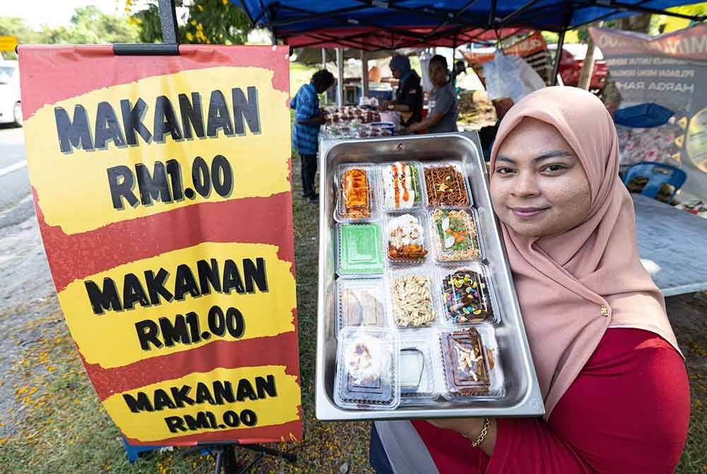 Nurul menunjukkan antara makanan yang dijual dengan harga RM1 di gerainya di Klebang Jaya, di Ipoh. Foto Bernama