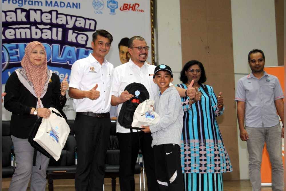 Muhammad Faiz (dua dari kiri) menyampaikan bantuan persekolahan Program MADANI Anak Nelayan Kembali ke Sekolah LKIM-BHPetrol bagi Persatuan Nelayan Kawasan (Hilir Perak) di Dewan Dato&#039; Mohammad Jamrah, Sungai Sumun, Bagan Datuk pada Sabtu.