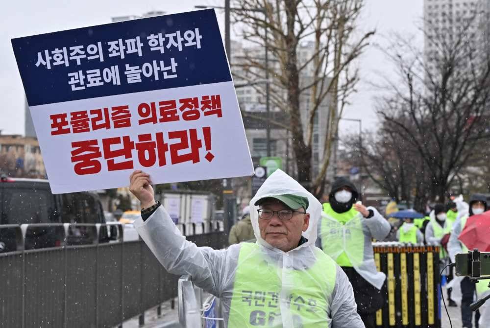 Seorang doktor memegang plakad tertera &#039;hentikan dasar perubatan populis&#039; ketika protes di Seoul pada 21 Februari lalu. Foto AFP