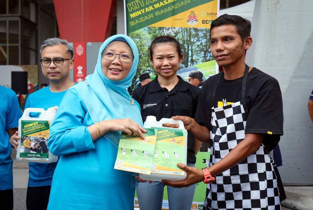 Menteri di Jabatan Perdana Menteri (Wilayah Persekutuan) Dr. Zaliha Mustafa (dua, kiri) menyampaikan botol dan risalah kepada peniaga bazar Ramadan pada program kempen kitar semula minyak masak terpakai sempena Program Teh Hijau Kuala Lumpur Edisi Mac 2024 di Stadium Bola Sepak Cheras pada Sabtu. Turut hadir, Menteri Komunikasi Fahmi Fadzil (kiri). Foto Bernama