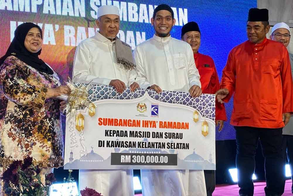 Ahmad Zahid (dua dari kiri) menyampaikan sumbangan kepada penerima semasa Majlis Iftar Santunan Kasih Ramadan di Masjid Batang Merbau di Tanah Merah pada Sabtu.