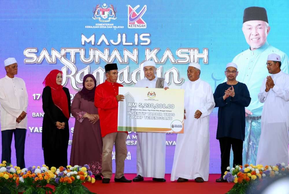 Ahmad Zahid (empat dari kanan) menyerahkan insentif tadbir urus kepada JPKKP Terengganu bernilai RM5.2 juta pada Majlis Santunan Kasih Ramadan bersama Kementerian Kemajuan Desa dan Wilayah 2024 di Masjid Sultan Mahmud Bandar Al Muktafi Billah Shah. Foto Bernama