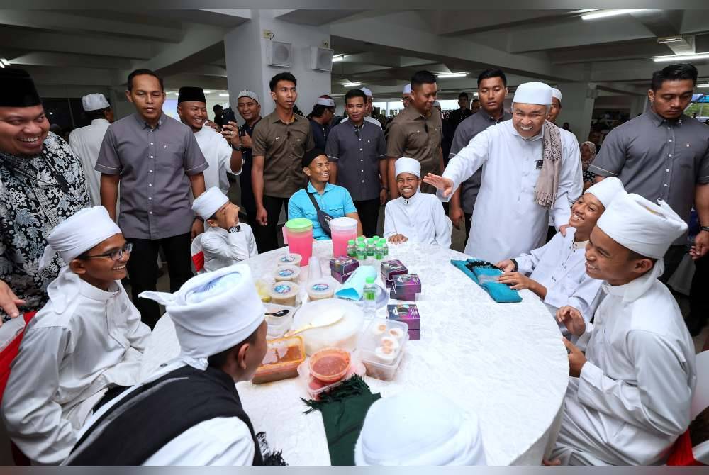 Ahmad Zahid (berdiri, dua dari kanan) menyantuni pelajar-pelajar tahfiz pada Majlis Santunan Kasih Ramadan bersama Kementerian Kemajuan Desa dan Wilayah 2024 di Masjid Sultan Mahmud Bandar Al Muktafi Billah Shah. Foto Bernama