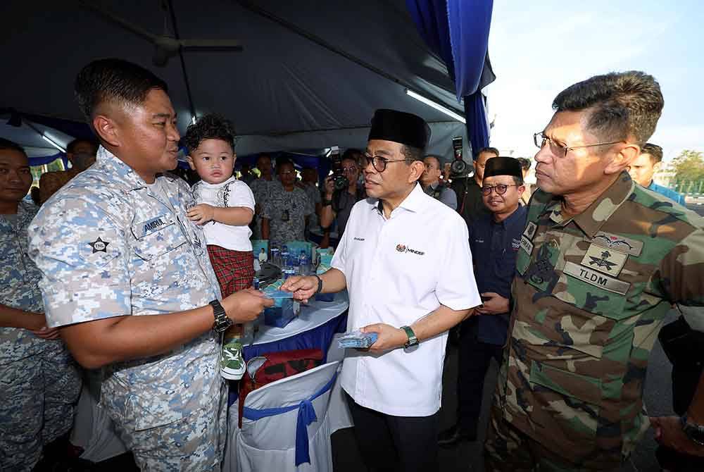 Mohamed Khaled diiringi Abdul Rahman (kanan) menyerahkan sumbangan kebajikan kepada anggota TLDM, Amirul Amir Hamja (dua dari kiri) dan anaknya, Izz Haikal Amirul, satu tahun enam bulan yang mengidap saluran darah ke paru-paru terlebih pada Majlis Berbuka Puasa Menteri Pertahanan Bersama Warga TLDM di Markas Pemerintahan Pasukan Simpanan TLDM Johor Bahru pada Ahad. Foto Bernama