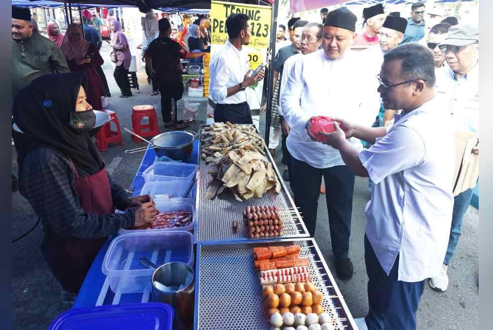 Amirudin (kanan) dan Rizam (dua dari kanan) mengagihkan Bubur Lambuk Rumpun Selangor di Bazar Ramadan Sungai Besar di sini pada Isnin.