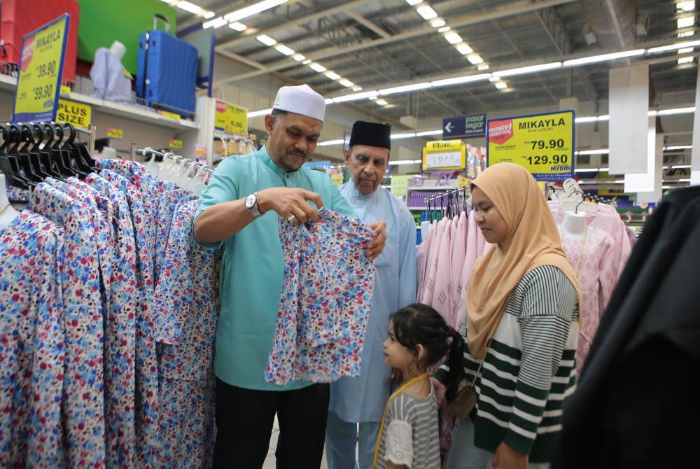 Muhammad Radhi (kanan) turut bersama penerima sumbangan memilih baju raya di Pasar Raya Mydin, Alor Setar pada petang Isnin.