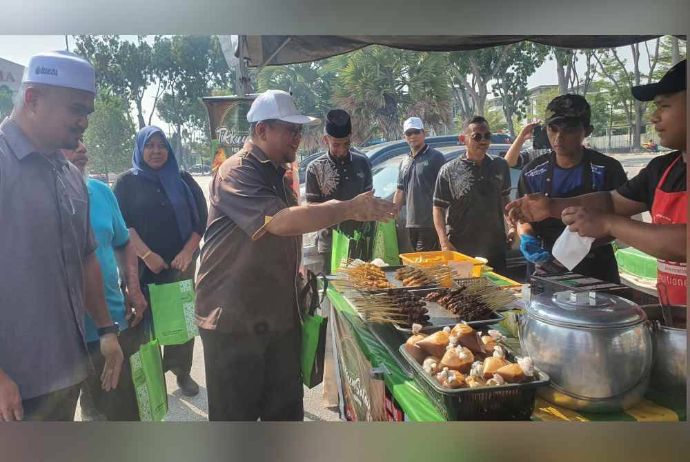 Amran (dua dari kiri) bersama Penyelaras DUN Seberang Jaya dan MPKK Jalan Baru menyantuni peniaga Bazar Ramadan Evoke pada Selasa.