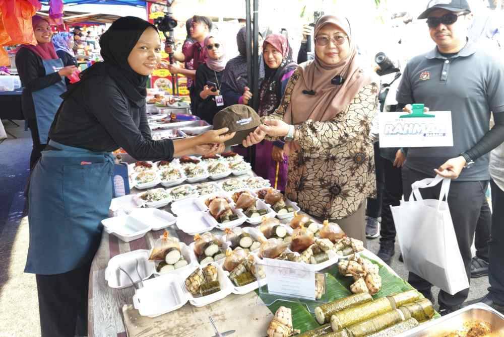 Fuziah (dua dari kanan) menyerahkan topi Rahmah kepada salah seorang peniaga semasa lawatannya dan Majlis Pelancaran Program MySaveFood di Bazar Ramadan Sungai Besar di sini pada Rabu.