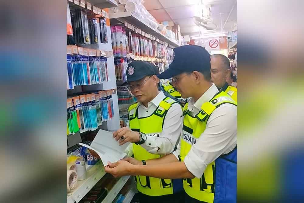 Mohd Fared (kanan) memeriksa alat tulis ketika operasi pemantauan di sebuah kedai serbaneka di Johor Bahru pada petang Rabu.