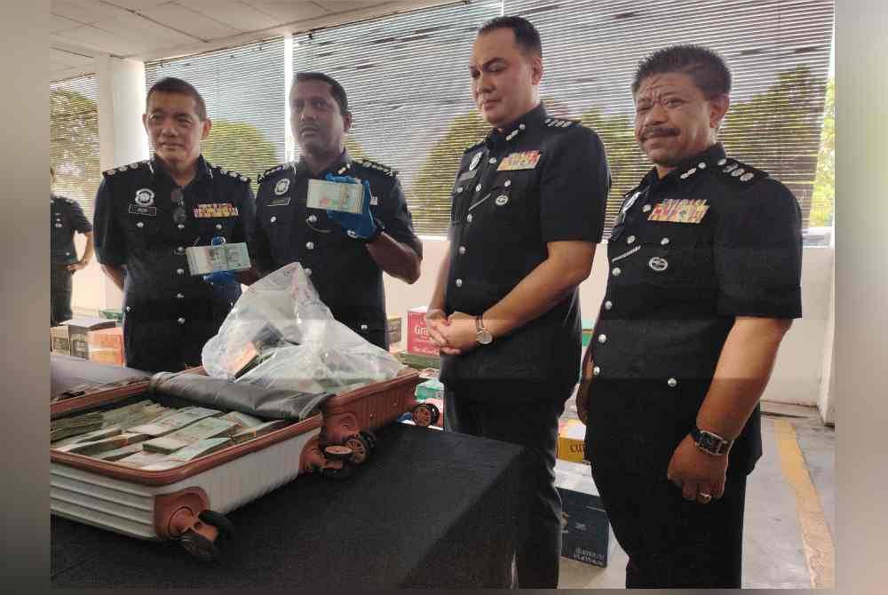 Hussein (dua kanan) menunjukkan wang tunai yang dijumpai dalam bagasi di tempat parkir di pusat beli-belah di Damansara, Petaling Jaya pada Rabu.