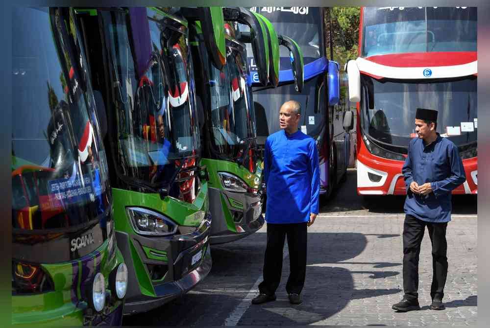 Che Ibrahim (kiri) bersama pegawai melihat sebahagian deretan bas ekspres yang parkir selepas Majlis Penyampaian Sumbangan Zakat E-Mutiara di Ibu Pejabat Konsortium E-Mutiara Berhad pada Khamis. Foto Bernama