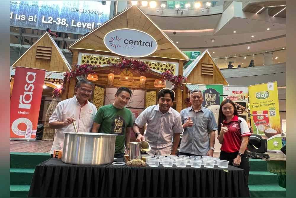 Dari kiri: Abdul Razak, Syamil Fahim, Mohd Najwan, Madiyan dan Mei Jen melakukan gimik menuang bubur lambuk ketika program edaran bubuk lambuk dan kuih warisan Majalah Rasa di sebuah pusat beli-belah di Shah Alam pada Sabtu.