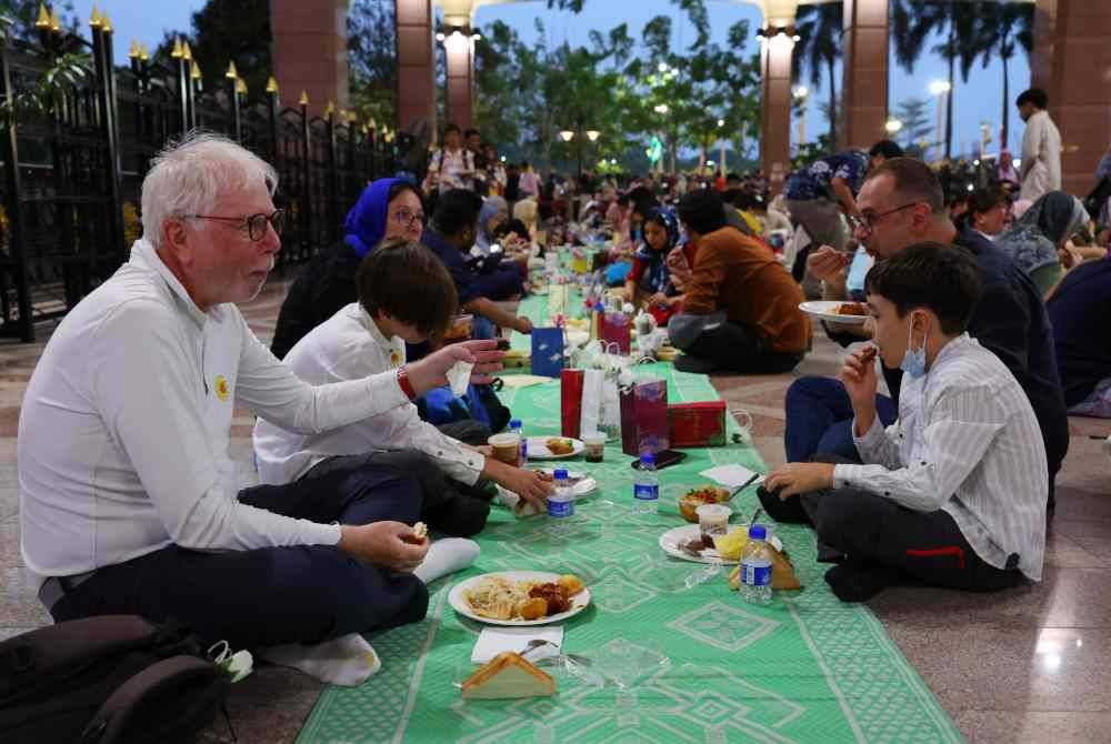 Para pelancong menjamu selera pada Majlis Iftar Masjid Putra Putrajaya bersama warga bukan Islam pada Sabtu. Foto Bernama