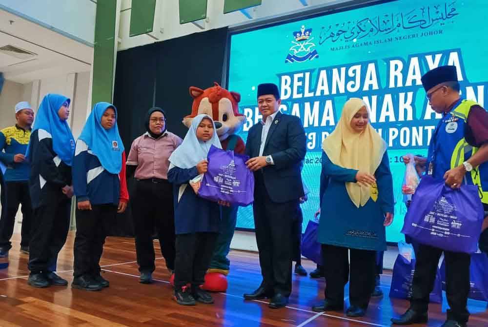 Nasri menyampaikan sumbangan kepada penerima dalam Program Belanja Raya Bersama Anak-anak Asnaf MAINJ Daerah Pontian di Pasar Raya Mydin, Mutiara Rini, Johor Bahru pada Ahad.