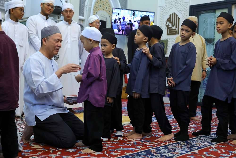 Fadillah (kiri) menyampaikan sumbangan kepada anak-anak yatim dan pelajar tahfiz pada Program Iftar Bersama Anak Yatim dan Tahfiz di Masjid Al-Ghazali. Foto Bernama