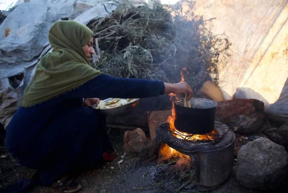 Bayan menyediakan hidangan itu di ruang memasak terbuka berhampiran khemah keluarganya. Foto Agensi