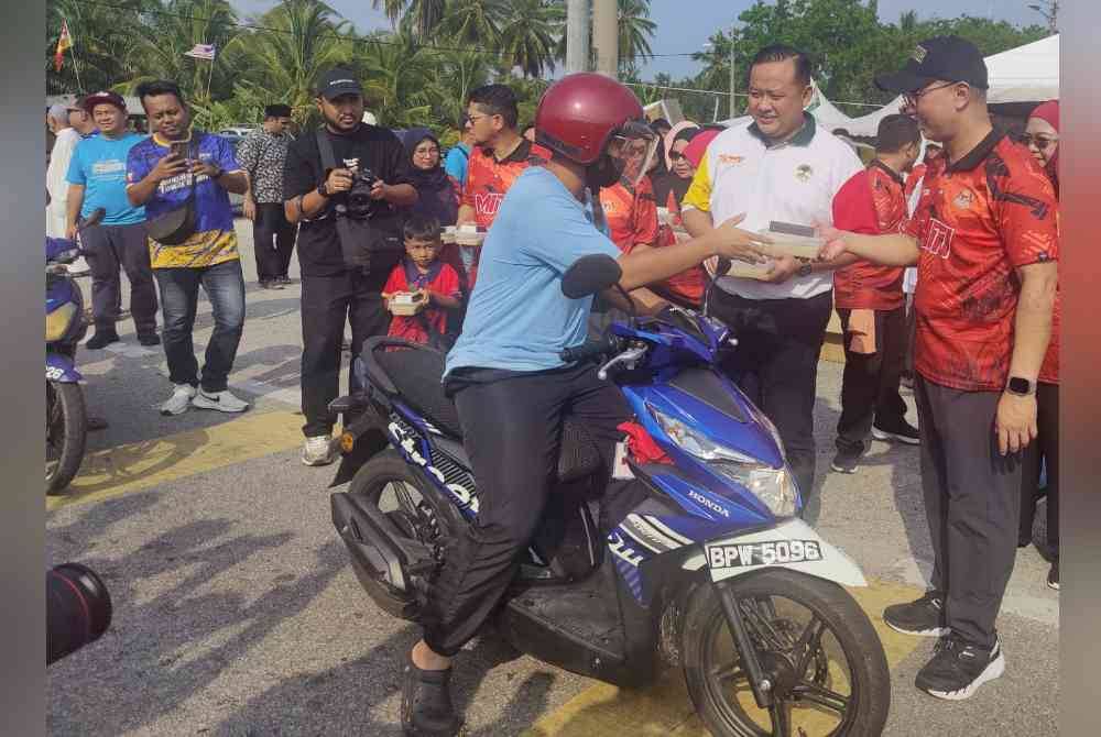 Tengku Zafrul (kanan) mengedarkan bubur lambuk kepada penduduk di Bagan Nakhoda Omar di sini pada Ahad.