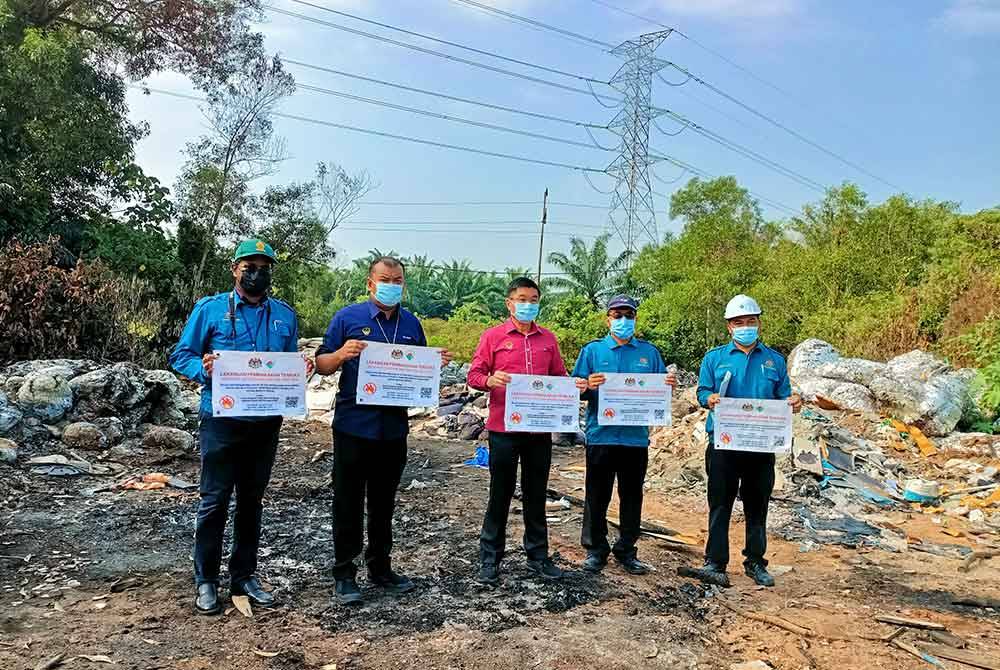 Kok Lim (tengah) menunjukkan papan tanda larangan aktiviti pembakaran terbuka yang dipasang di tapak sampah haram di Kawasan Perindustrian Gopeng semasa tinjauan pada Isnin.