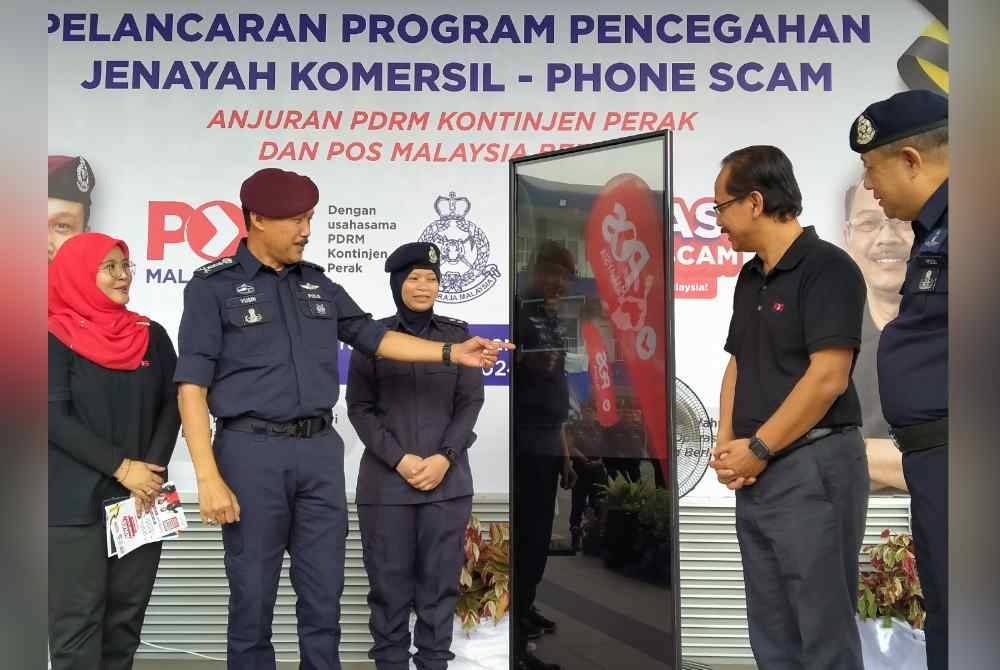 Mohd Yusri (dua dari kiri) menyempurnakan gimik Majlis Pelancaran Program Pencegahan Jenayah Komersil Phone Scam - Penyamar Pos Malaysia di Ibu Pejabat Polis Kontinjen Perak di sini pada Selasa.