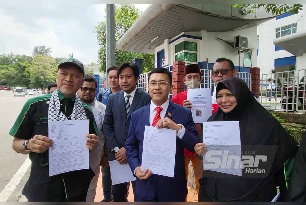 Borhan (dua dari kanan) menunjukkan laporan polis yang dibuat di IPD Shah Alam, pada Rabu.