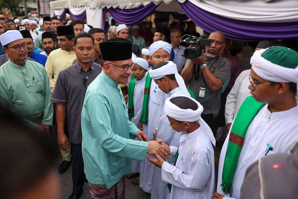 Anwar beramah mesra dengan pelajar tahfiz dari Pondok Tok Mengkarak Bera Pahang yang hadir ke Majlis Berbuka Puasa bersama Perdana Menteri di Masjid Ashabus Solihin Taman Rakan Kajang malam Rabu. Foto Bernama