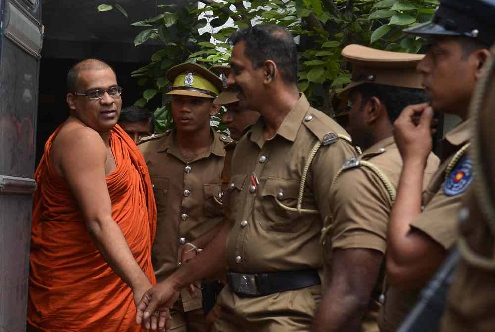 Polis Sri Lanka mengawal sami Buddha, Galagodaatte Gnanasara selepas dijatuhi hukuman penjara atas kesalahan menghina mahkamah pada 2018. - AFP