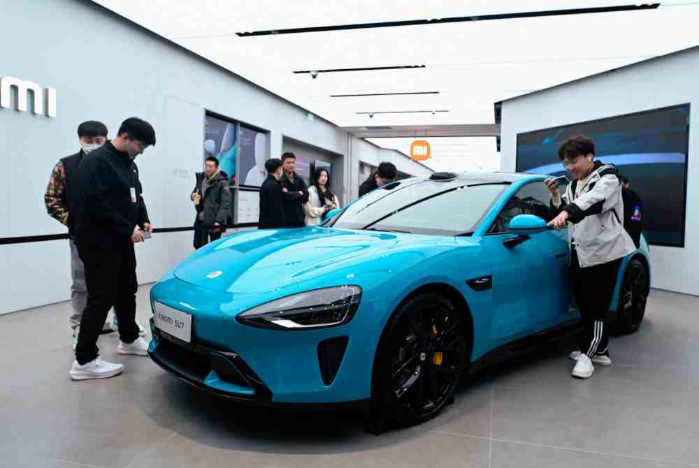 Orang ramai melihat kereta elektrik Xiaomi SU7 yang dipamerkan di kedai Xiaomi di Beijing. Foto AFP