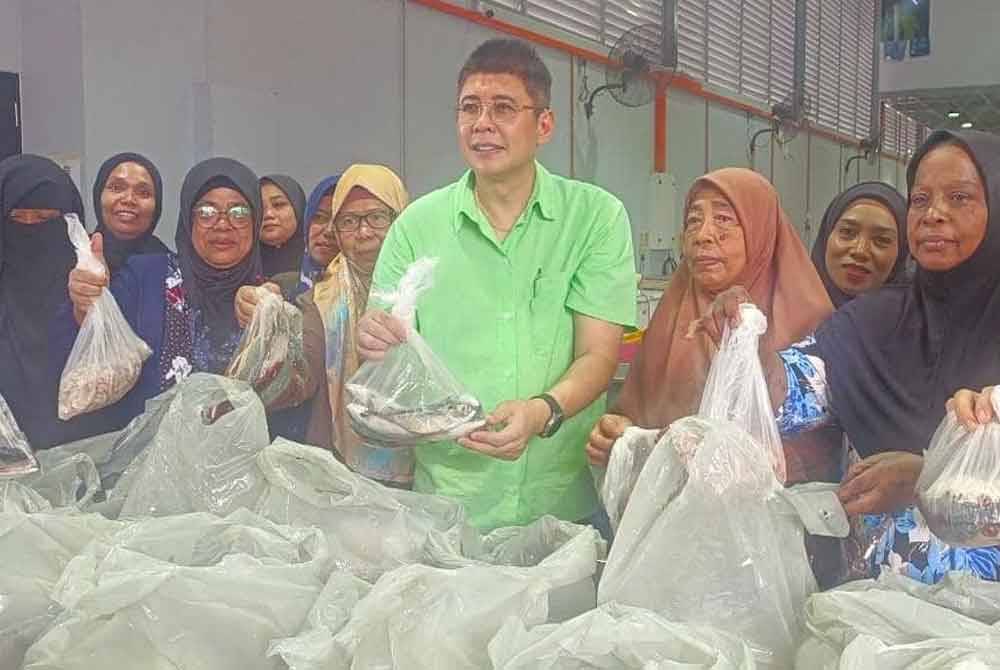 Dr Gary Ko (tengah) menyerahkan makanan laut percuma kepada penerima daripada PPR Stulang Laut di premisnya di GM Seafood, Taman Mount Austin, Johor Bahru pada Jumaat.