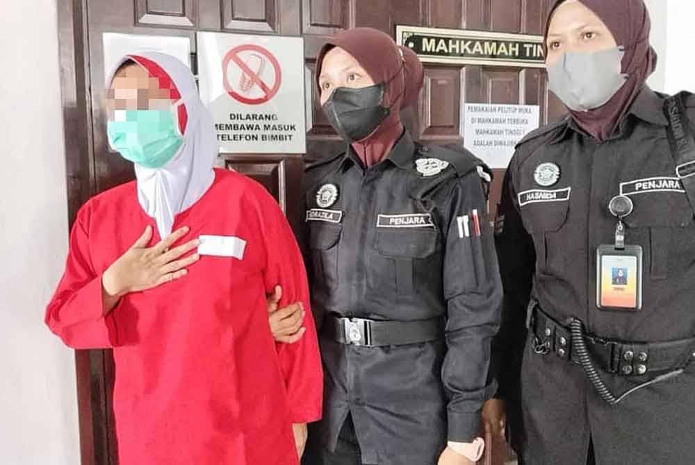 Wanita berkenaan (kiri) sebak ketika dibawa keluar dari Mahkamah Tinggi Melaka pada Jumaat.