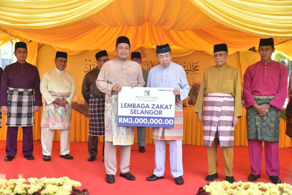 Sultan Selangor (depan, kanan) mewakili LZS menerima serahan zakat perniagaan daripada Zainudin (depan, kiri) pada Majlis Berbuka Puasa dan Penyerahan Sumbangan serta Penyerahan Zakat di Masjid Kota Kemuning di sini pada Khamis.