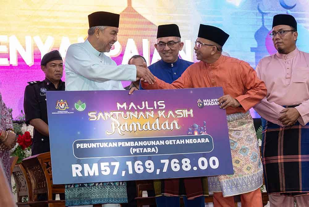 Ahmad Zahid menyampaikan peruntukan bagi program pembangunan getah negara sebanyak RM57.169 juta kepada Ketua Pengarah Risda, Datuk Abdullah Zainal (dua dari kanan) pada Majlis Santunan Kasih Ramadan di Kompleks UMNO Bagan Datuk pada Jumaat. Foto Bernama