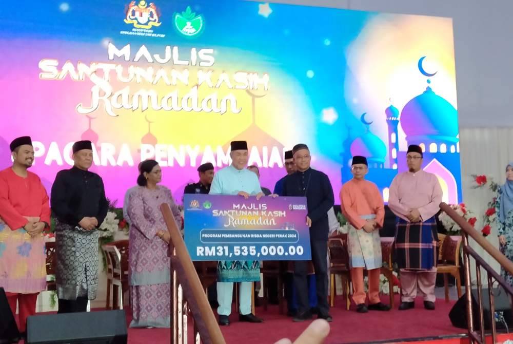 Ahmad Zahid (empat dari kiri) menyerahkan peruntukan bagi Program Pembangunan RISDA negeri Perak sempena Majlis Santunan Kasih Ramadan di Dewan Perdana, Kompleks UMNO Bahagian Bagan Datuk pada Jumaat.