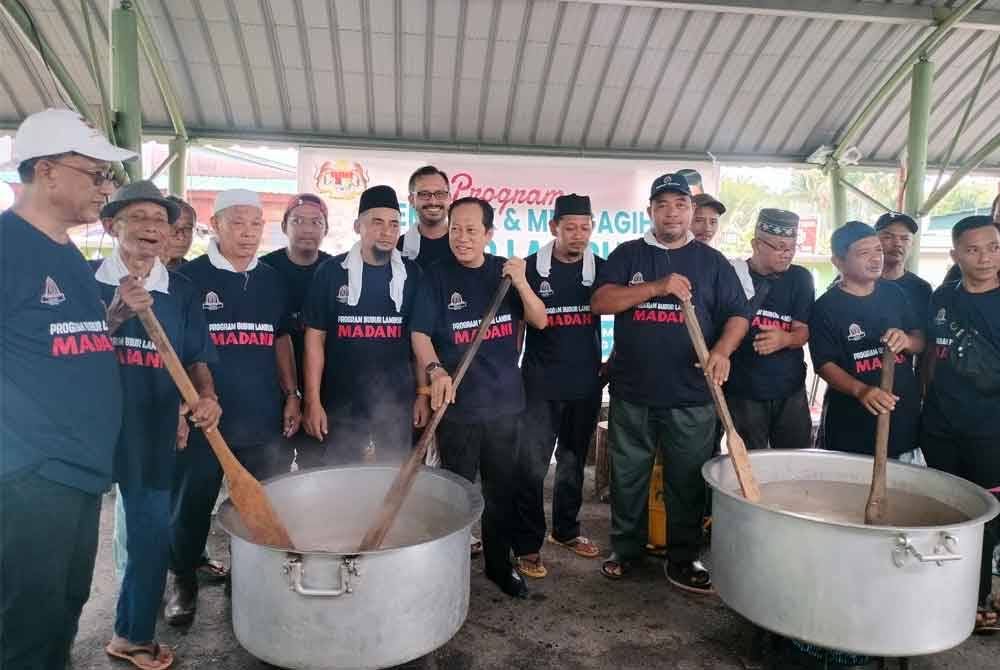 Ahmad (tengah) memasak bubur lambuk Madani di Kampung Parit Mansor, Benut pada Sabtu.