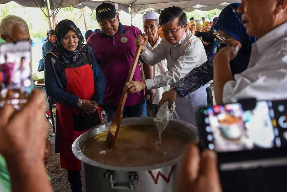 Kon Yeow bersama penduduk setempat memasak bubur lambuk pada Program Bubur Lambuk bersama Ketua Menteri Pulau Pinang di Masjid Jamiul Sharif Pokok Machang pada Sabtu. Foto Bernama