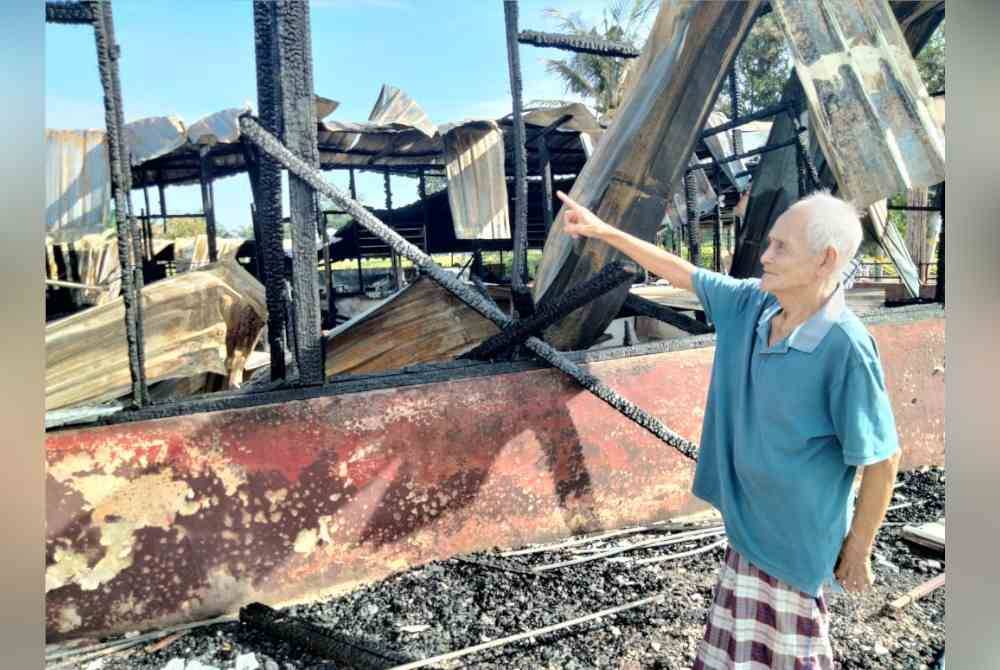 Rosnin menunjukkan rumah yang hangus terbakar dalam kejadian di Kampung Parit Selangor, Pontian.