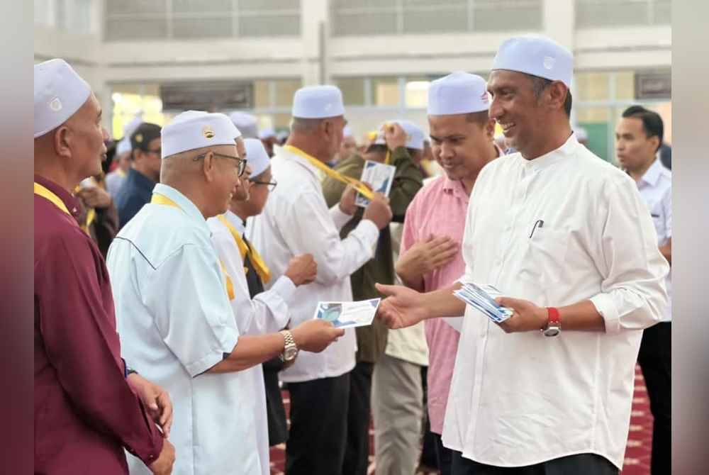 Syed Ibrahim (kanan) menyampaikan bantuan khas Aidilfitri kepada imam, bilal dan siak dari Wilayah Jengka, Semantan, Lanchang, Mentakab, Bera dan Maran pada majlis penyampaian di Masjid Sultan Ahmad Shah, Temerloh pada Ahad.