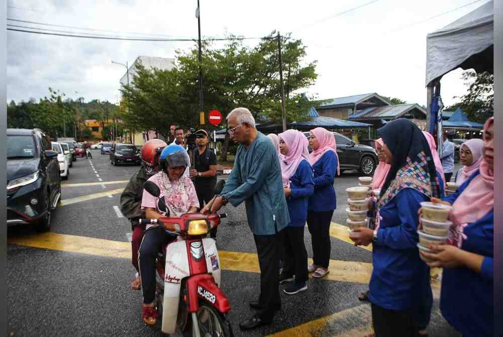 Mahdzir mengedarkan bubur lambuk kepada orang ramai di pekarangan pejabat UMNO Padang Terap pada Sabtu.