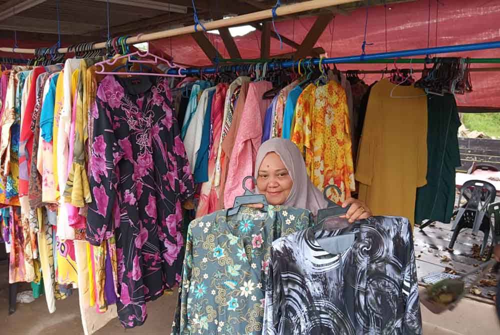 Fatimah menunjukkan baju kurung yang terdapat warungnya untuk diberikan percuma kepada mereka yang kurang berkemampuan.