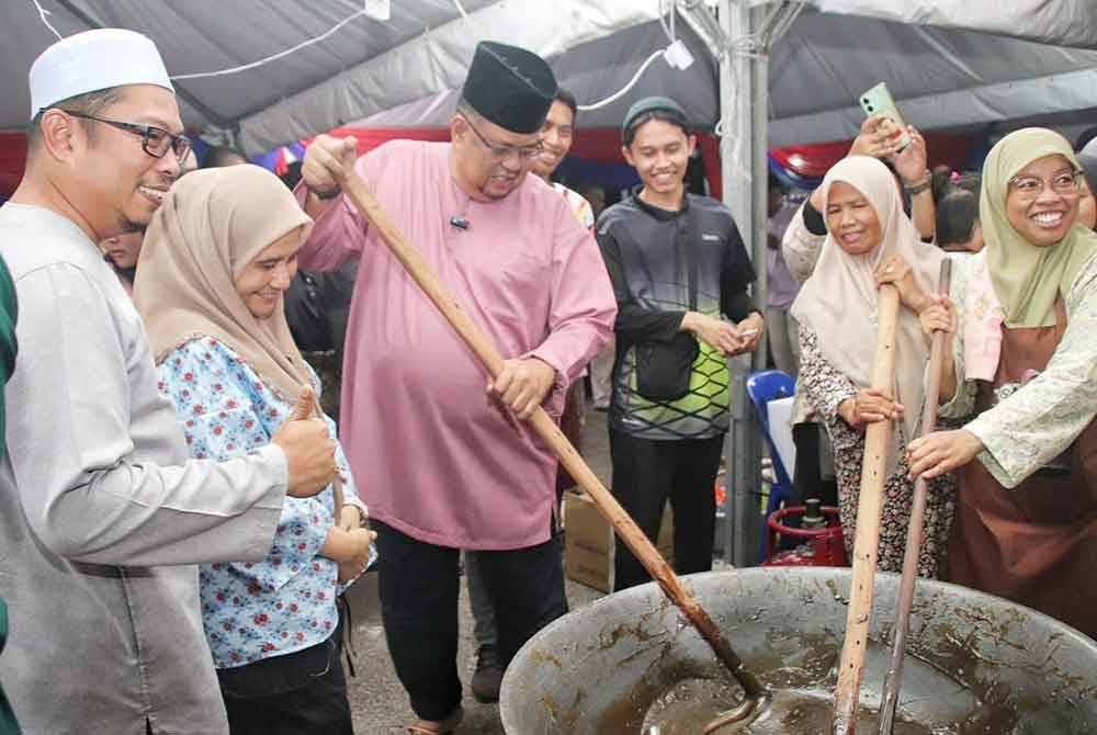 Ab Rauf (tiga dari kiri) mengacau dodol di Festival Kuih Tradisional Aidilfitri dan Pelita Raya Melaka di Sungai Rambai Riverside, di Jasin pada malam Ahad.