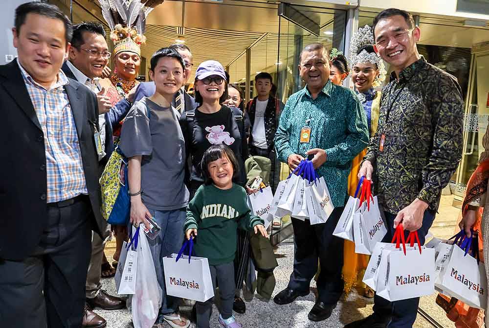 Manoharan (dua dari kanan) bergambar bersama para penumpang penerbangan Sichuan Airlines sejurus tiba di KLIA Terminal 1 dari Chengdu, China pada malam Ahad. Foto Bernama