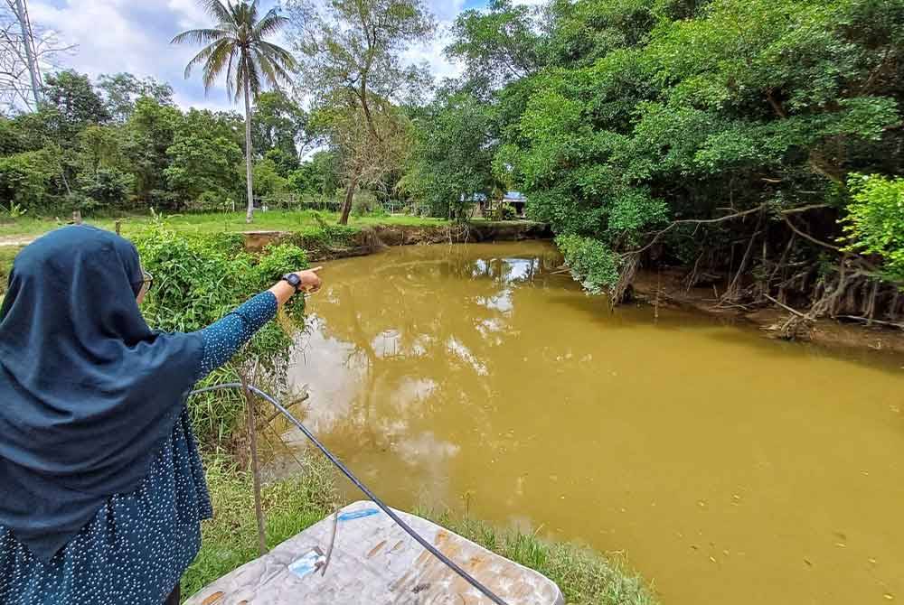 Seorang penduduk menunjukkan kelibat dua ekor buaya kelihatan di Sungai Belat berhampiran rumahnya pada Ahad.