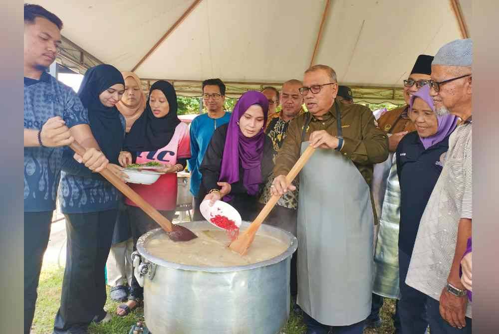 Mohd Zolkafly (tiga dari kanan) bersama Tina (empat dari kanan) mengacau bubur lambuk sempena program agihan bubur lambuk anjuran TT Group bersama gabungan 10 pertubuhan bukan kerajaan (NGO) pada Selasa.