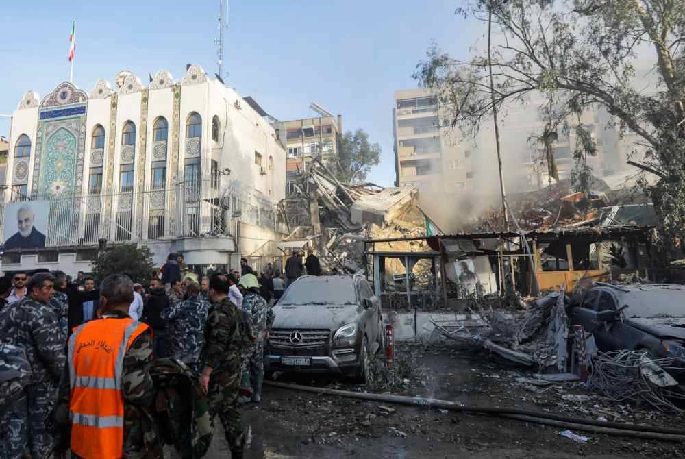 Pihak berkuasa meninjau lokasi bedilan misil yang menyasarkan bangunan tambahan di Kedutaan Iran di Damsyik pada Isnin. Foto AFP