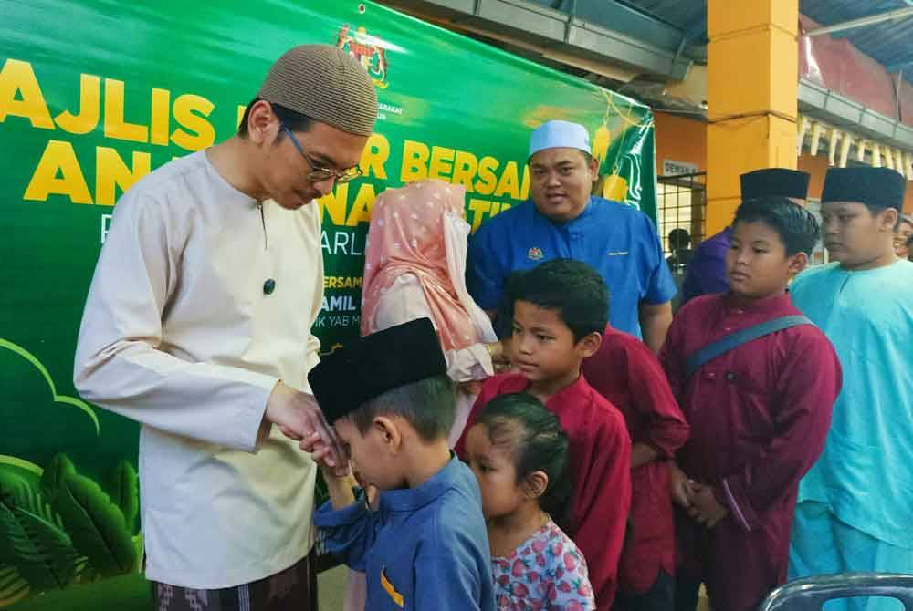 Muhammad Kamil (kiri) menyantuni anak-anak yatim Rumah Anak Yatim An Nur Maisarah sempena program berbuka puasa pada Selasa.