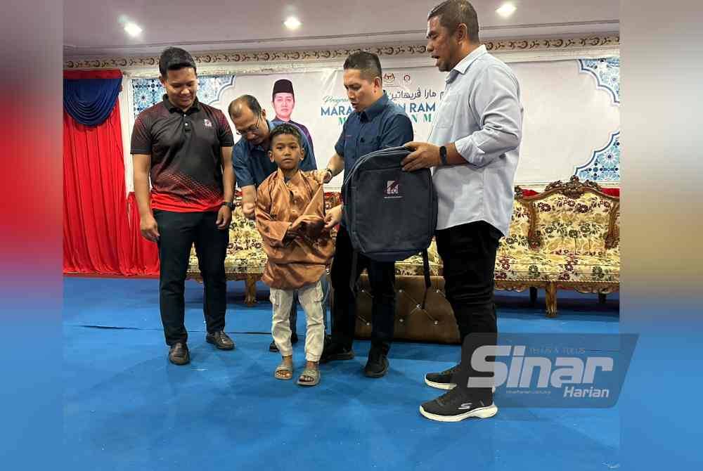 Noor Hariri (dua dari kanan) membantu seorang penerima kanak-kanak mencuba baju raya.