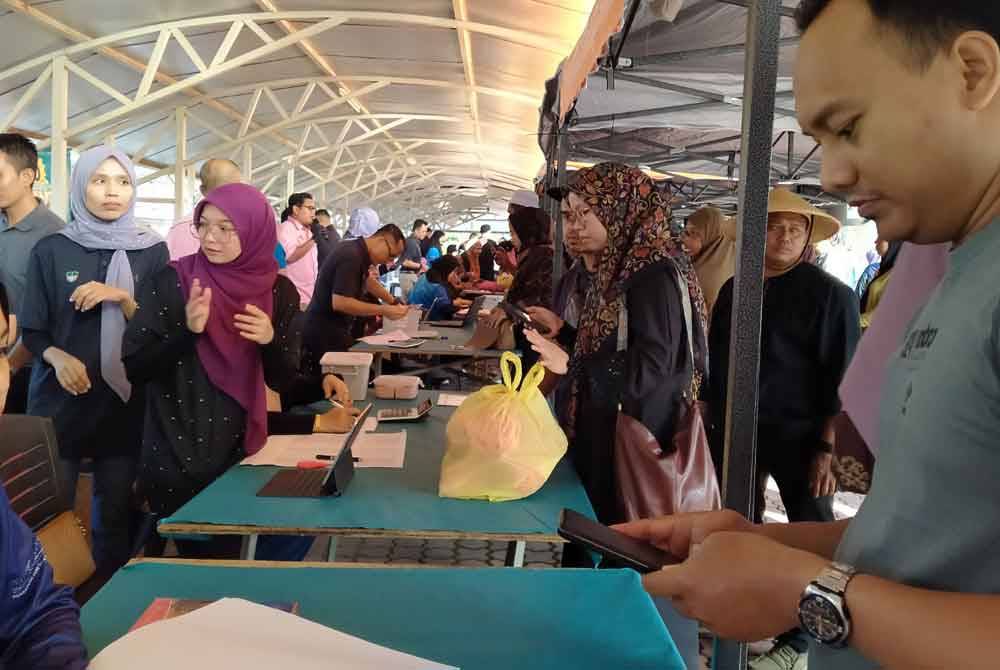 Orang ramai mendapatkan barangan keperluan sempena Program Jualan Rahmah Aidilfitri di pekarangan parkir Ibu Pejabat Perak SADC di sini pada Khamis.