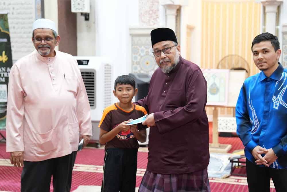 Mohd Radzif (dua dari kanan) menyampaikan sumbangan duit raya kepada salah seorang pelajar.