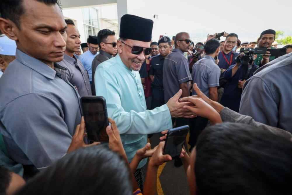 Perdana Menteri Datuk Seri Anwar Ibrahim bersalaman dengan jemaah selepas menunaikan solat Jumaat di Masjid Al-Huda Sungai Ara hari ini. Foto Bernama
