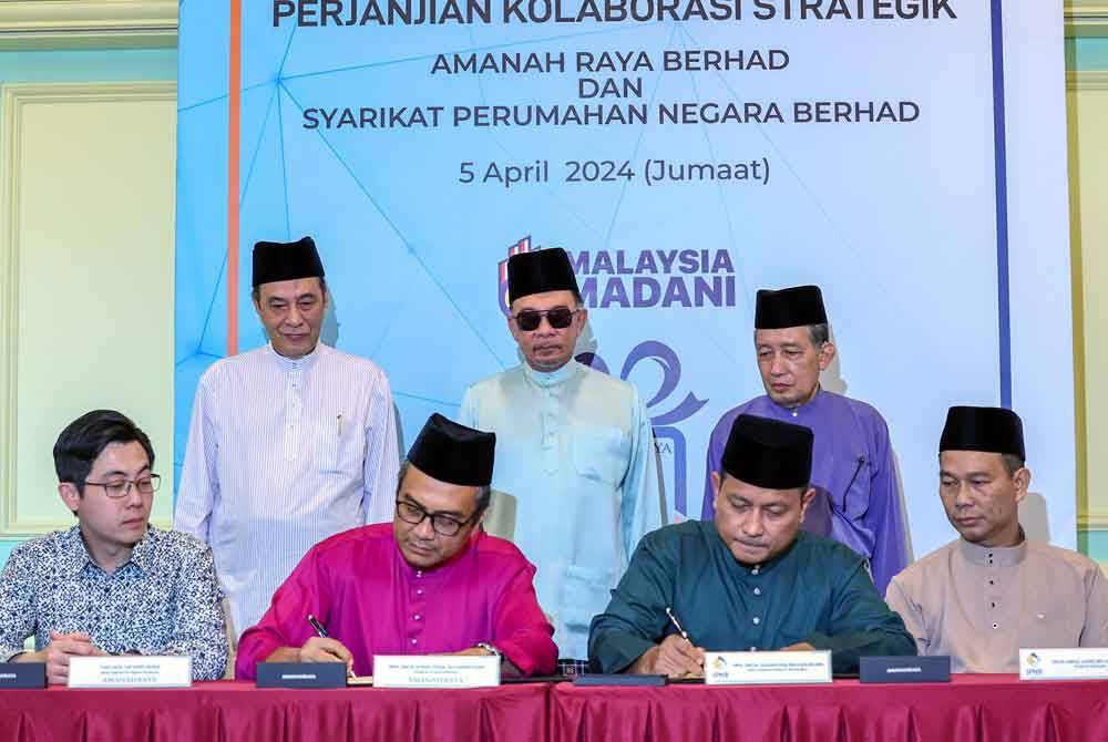 Anwar (berdiri, tengah) menyaksikan majlis pertukaran dokumen perjanjian kolaborasi strategik antara AmanahRaya dengan SPNB di Bangunan Perdana Putra pada Jumaat. Foto Bernama